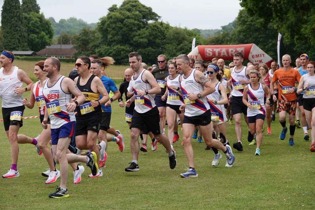 Large group of runners running across a field at the start of the 2022 Beer Race