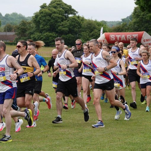 Large group of runners running across a field at the start of the 2022 Beer Race
