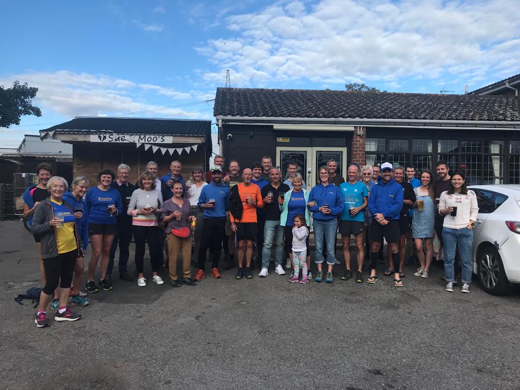 A large group of runners stood outside of a pub