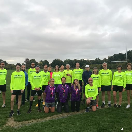 21 runners mostly in yellow clarendon shirts with 3 in purple london shirts standing in a field