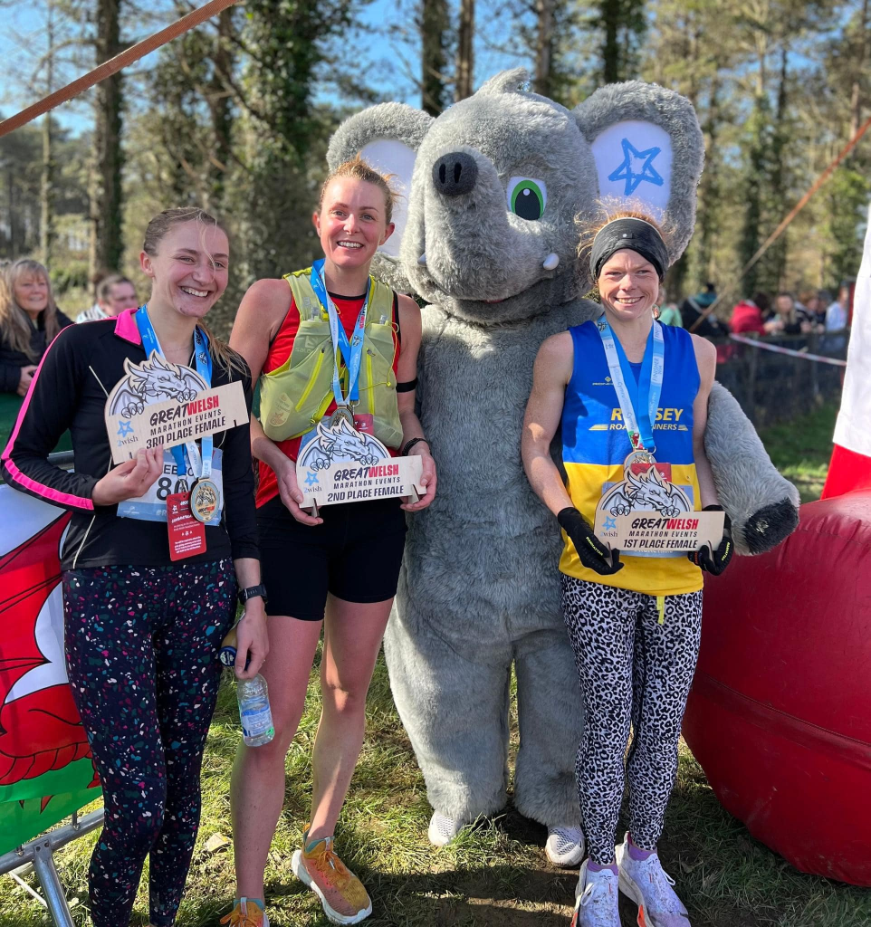 Hayley and two other female runners with their trophies and a person dressed as an elephant