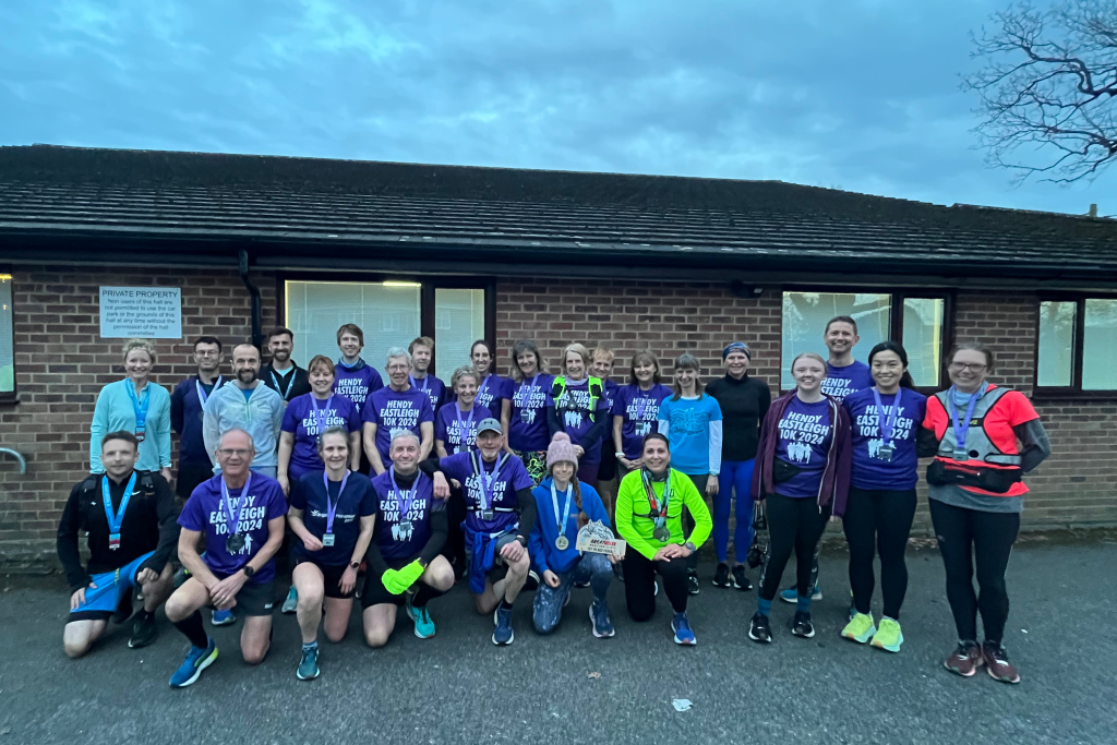 Lots of runners, mostly in purple shirts and medals outside a village hall