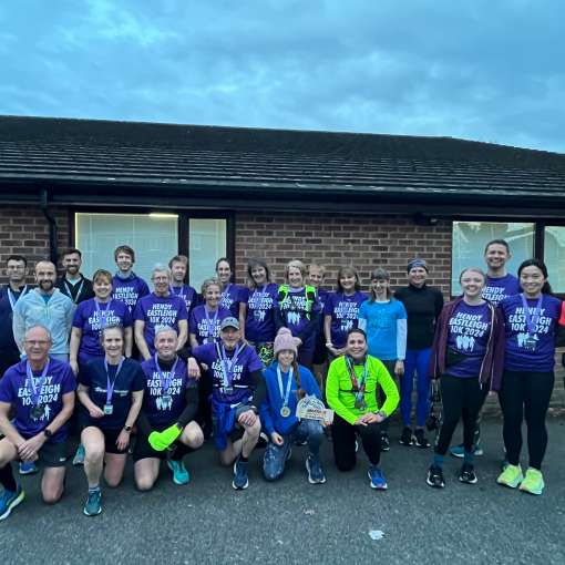 Lots of runners, mostly in purple shirts and medals outside a village hall